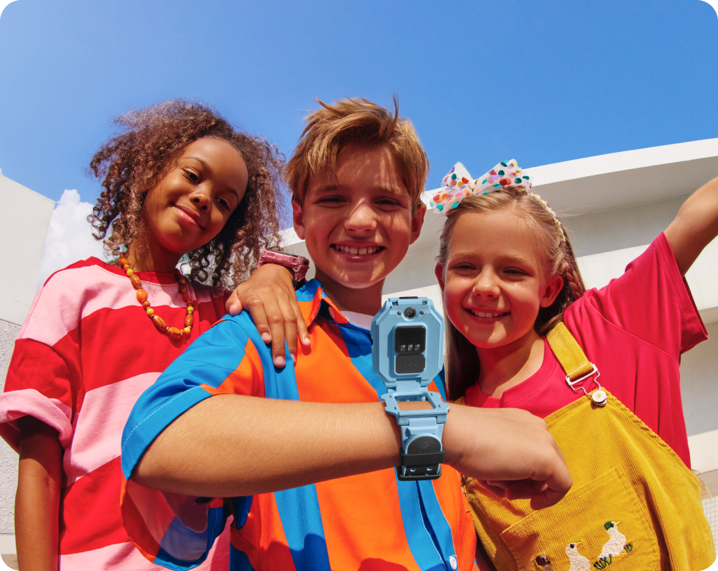 Drei lachende Kinder im Freien, Junge trägt imoo Watch Phone Z7 mit Flip-Design und Doppelkamera.